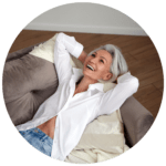 Woman reclining on couch smiling and thinking about how much her women's nutrition plan has helped her sail smoothly through menopause.